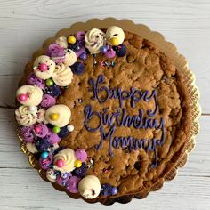 a birthday cake decorated with cookies and candies on a white wooden surface, which reads happy birthday mommy