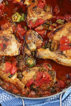 a pan filled with chicken and vegetables on top of a blue towel