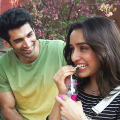 a man and woman sitting next to each other holding a bottle with a toothbrush in it