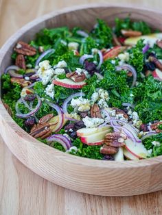 a wooden bowl filled with vegetables and nuts