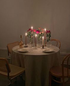 a table with candles and flowers on it in the middle of a dining room area