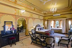 an ornate bedroom with chandelier, bed, and tv in it's center