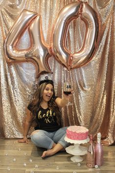 a woman sitting on the floor in front of a cake and balloons that say 40