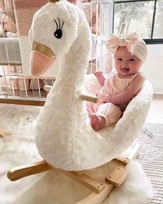 a baby is sitting in a rocking horse with a swan on it's back