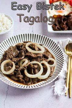 a white plate topped with meat and onions on top of a table next to rice