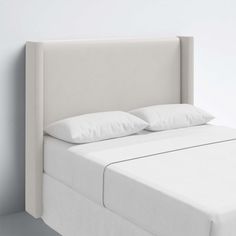 a white bed with two pillows on top of it