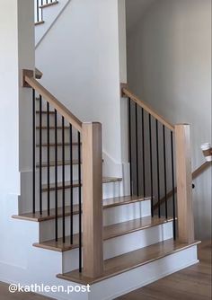 an empty staircase with wooden handrails and white walls