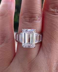 a woman's engagement ring with an emerald and baguette cut diamond in the center