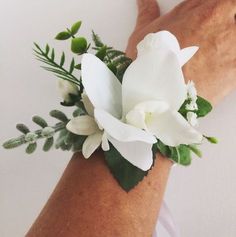 a woman's arm with a white flower and greenery on it