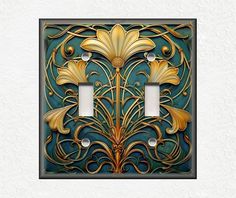 an intricately designed light switch plate cover in gold and teal with two lights