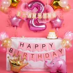 a pink birthday party with balloons, decorations and an elephant table cloth on the table