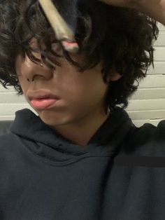 a young man brushing his hair with an electric blow dryer