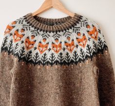 an orange and black sweater hanging on a wooden hanger