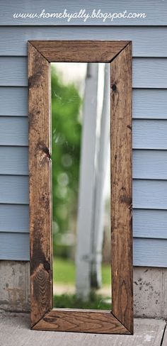 a wooden mirror sitting on the side of a blue wall next to a window sill