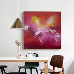 a painting hanging on the wall above a dining room table with chairs and vases