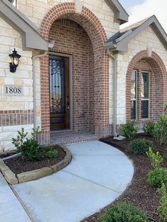 the front entrance to a brick home with landscaping around it and an entry way leading into the house