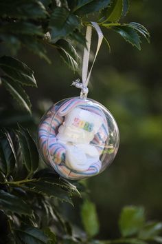 a glass ornament hanging from a tree filled with baby's diapers