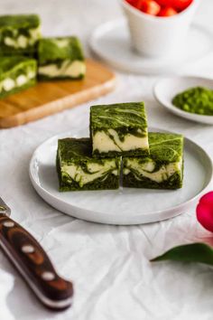 four pieces of green and white cake on a plate with flowers in the back ground