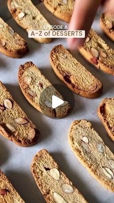 cookies with almonds are arranged in rows on a baking sheet, and then being sliced into smaller pieces