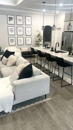 a living room filled with furniture next to a kitchen and dining room table covered in black and white pillows