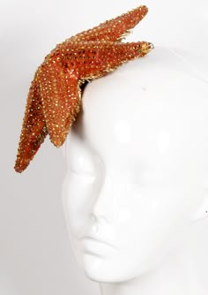 OR 4 interest-free installments of $350.00 USD by Crafted from foam filled thermoplastic, this one-of-a-kind headpiece is lightweight and versatile in terms of how you wear it. Its uniquely sculpted form has been hand painted and rhinestoned by the artist. The underside is as beautiful as the exterior, boasting a plethora of individually applied bugle and glass seed beads that realistically recreate the anatomy of an actual starfish but with a decidedly glamorous twist. Removable/adjustable clea Starfish Inspired Fashion, Nautical Costume, Portrait Props, Surrealist Fashion, Starfish Headpiece, Unique Fascinators, Beaded Hats, Patricia Field, Large Brim Hat