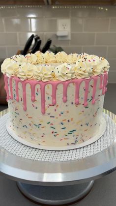 a cake with white frosting and sprinkles sitting on a counter top