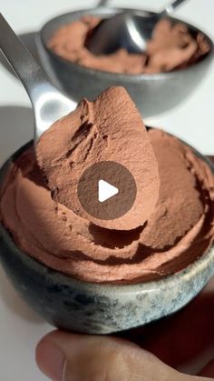 a hand holding a spoon over a bowl of chocolate ice cream with a video on it