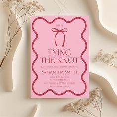 a pink card with a bow on it and the words tying the knot in red