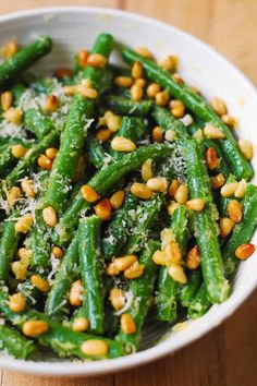 a white bowl filled with green beans covered in parmesan cheese