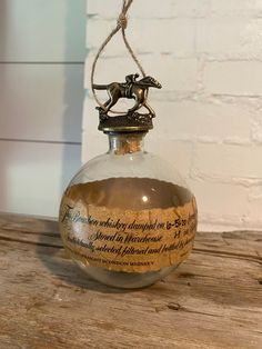 an old fashioned glass bottle with a horse on it's back and rope hanging from the top