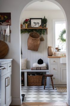 an archway leading into a kitchen with white cabinets and checkered flooring on the walls