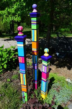 three tall colorful wooden sculptures in the grass