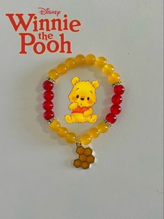 the winnie the pooh bracelet has been made from glass beads and is hanging on a wall