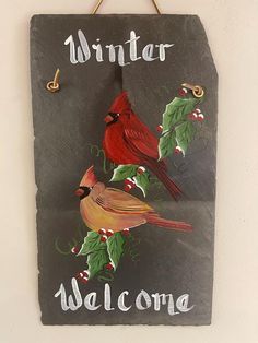 a welcome sign with two cardinal birds on it and holly leaves hanging from the front