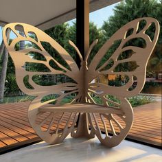 a large wooden butterfly sculpture sitting on top of a table next to a glass door