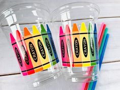 two clear cups filled with crayons and colored pencils