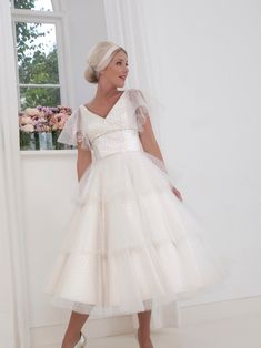 a woman in a white dress standing next to a window