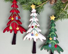 three felt christmas trees hanging from a tree branch