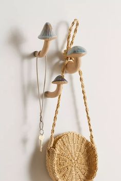 a basket hanging on the wall next to a hook with two mushrooms attached to it