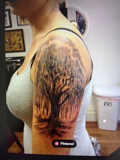 a woman's arm with a tree tattoo on the back of her left shoulder