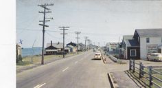 an old photo of a street with cars parked on the side and telephone poles in the background