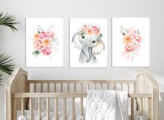 two paintings of an elephant with flowers on their head are hanging above a crib