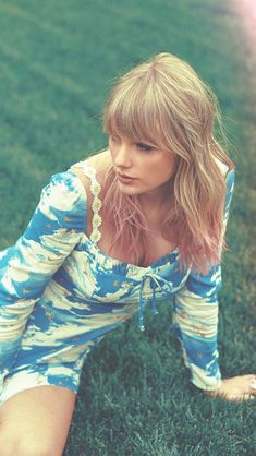 a beautiful young woman sitting on top of a lush green field