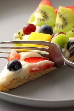 a piece of fruit pizza on a plate with a fork