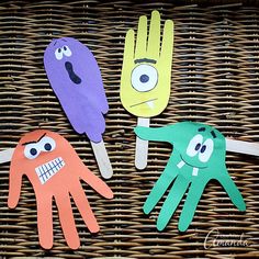 three handprinted paper puppets sitting on top of a wicker basket