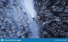 an aerial view of a car driving through the snow - covered forest in wintertime