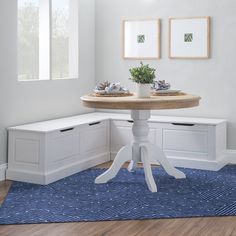 a corner table with two planters on it in front of a white wall and blue area rug