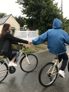 two people riding bikes in the street with one holding the hand of another person's hand