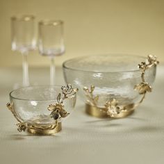 two glass bowls with gold decorations on them and one bowl has a wine glass in the middle