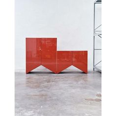 two red cabinets sitting next to each other in a room with metal shelving on the floor